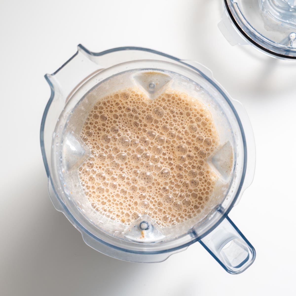 Blender container filled with frothy tofu milk mixture for apple pie baked oats.