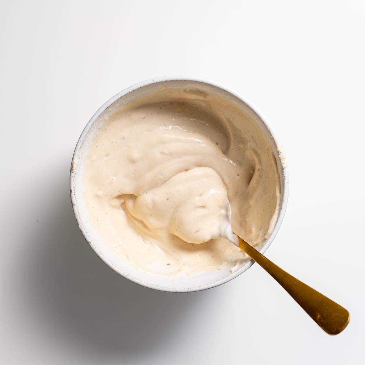 Creamy blended silken tofu milk mixture in a bowl with spoon for apple pie baked oats.