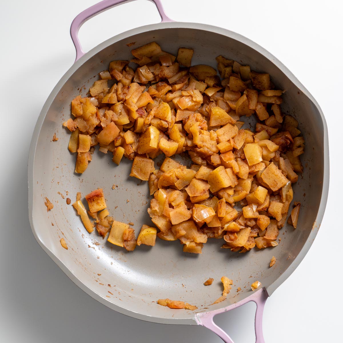 Stewed diced apples cooking in a skillet for apple pie baked oats.