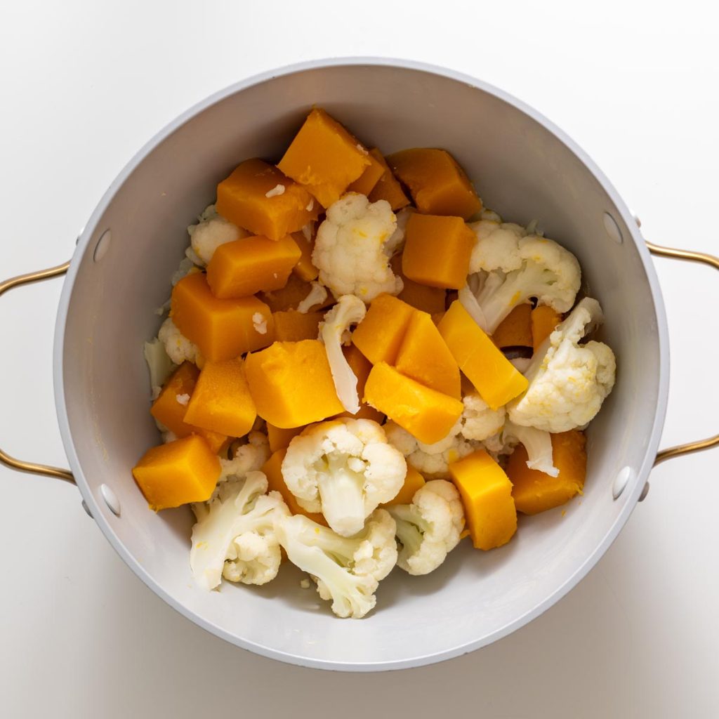pot with boiled butternut squash and cauliflower florets ready for mashing