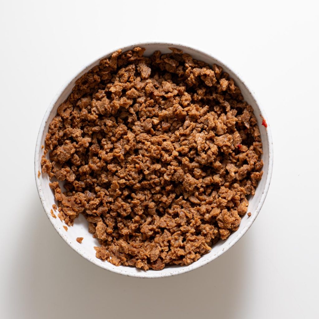 bowl of cooked textured vegetable protein (tvp) crumbles on a white surface