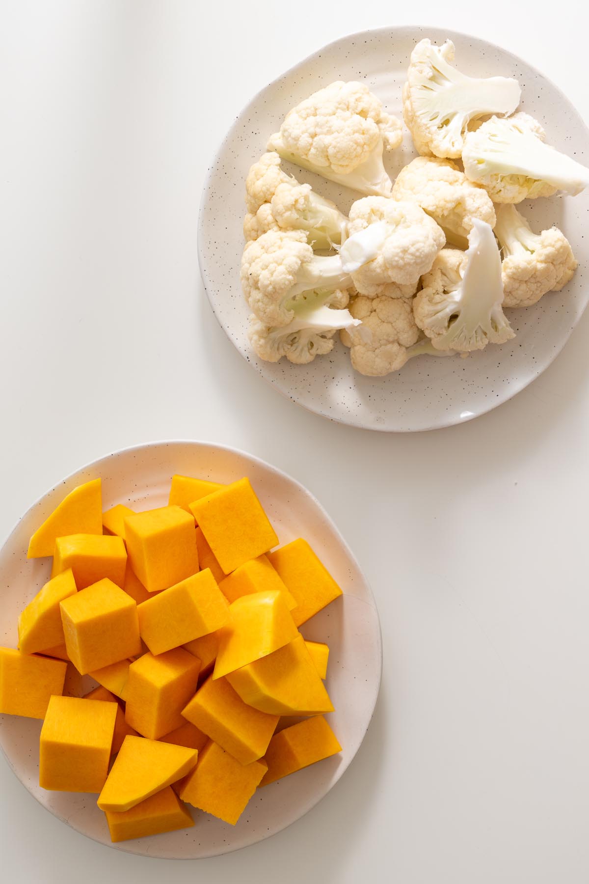 plate of cauliflower florets and plate of cubed butternut squash for mash