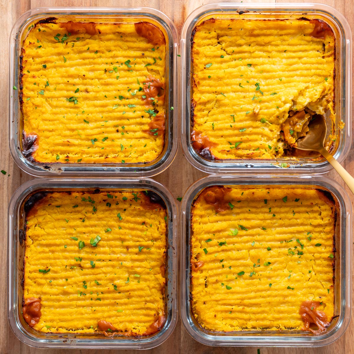 overhead of four baked shepherds pies in glass meal prep containers