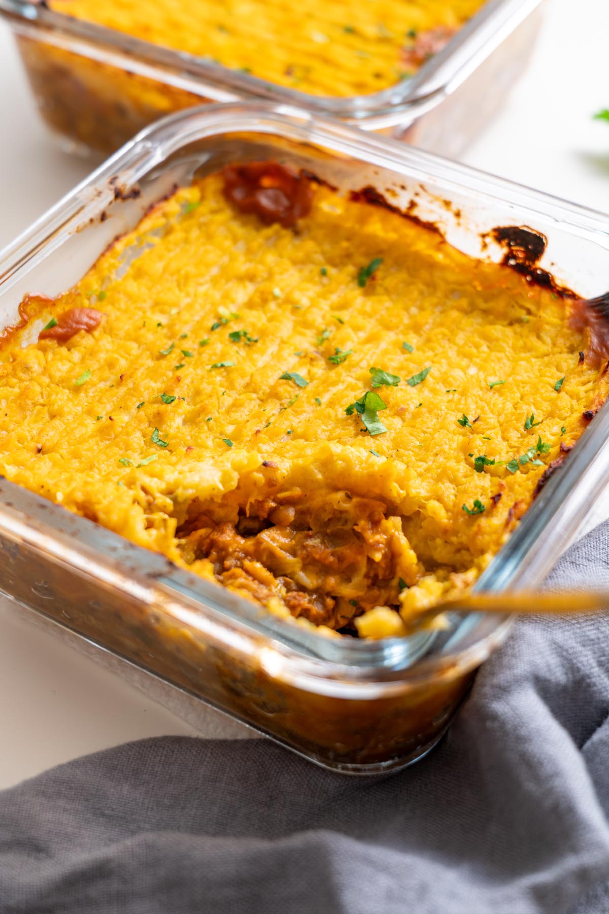 overhead of baked shepherds pie with parsley garnish and spoon inside the dish