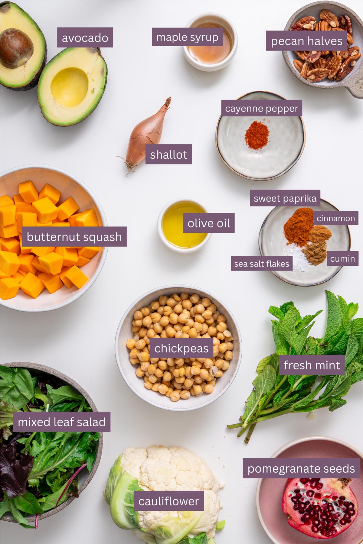 Nguyên liệu sống động cho món salad phong lễ hội trên bề mặt trắng – bí nướng, súp lơ trắng, đậu xanh, quả bơ, hạt lựu, kẹo hồ đào, rau trộn và nước sốt