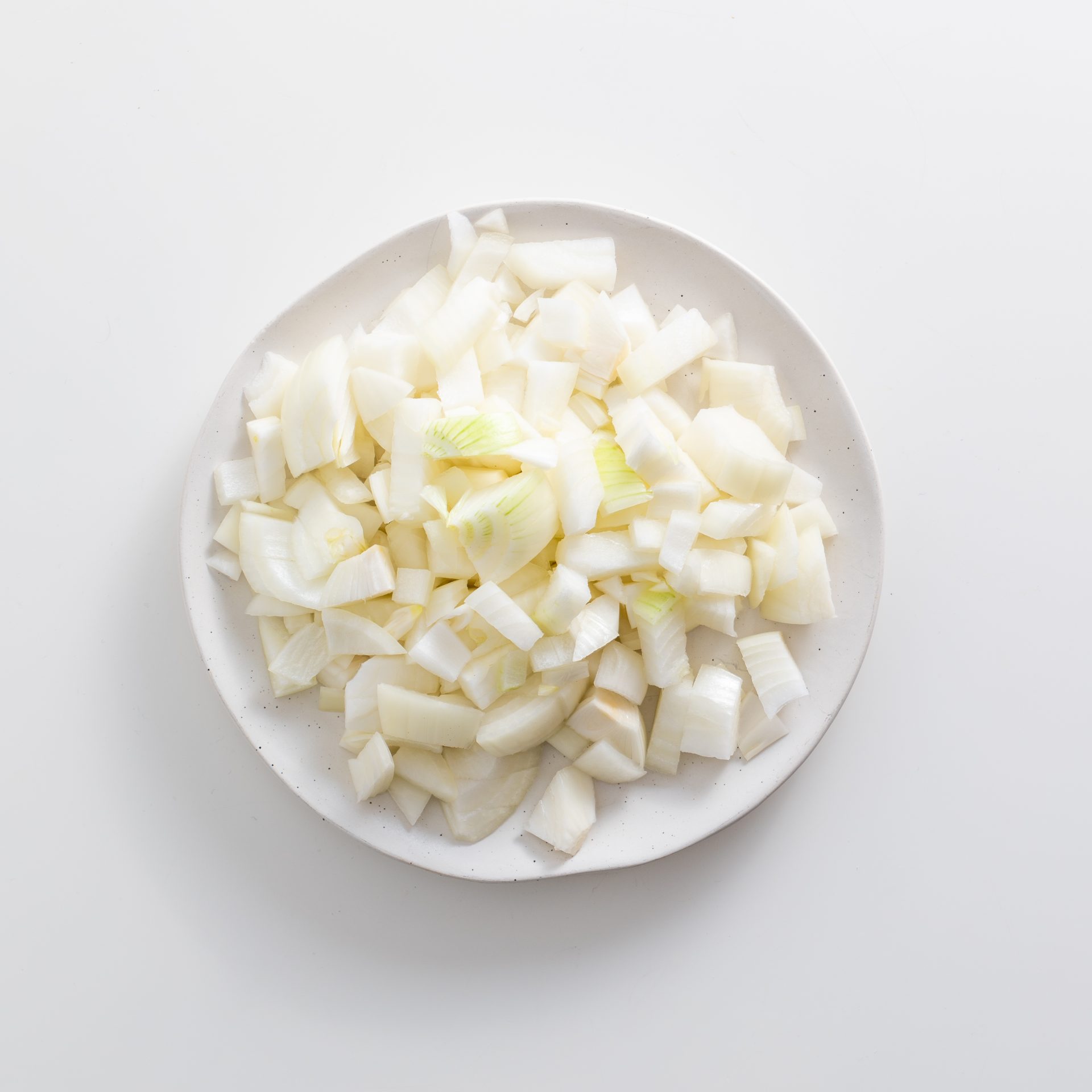 Plate of diced yellow onions ready to caramelize for vegan French onion dip