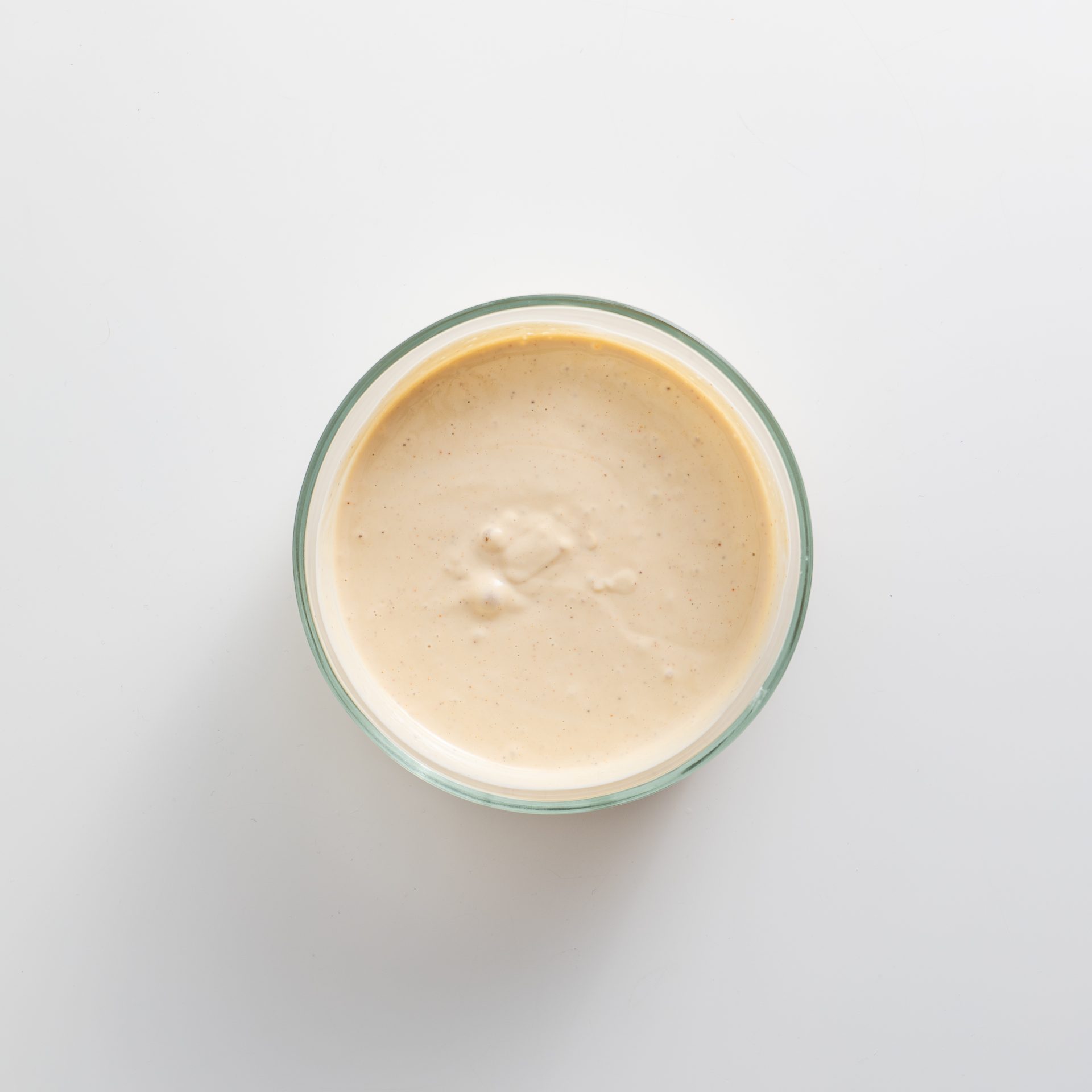 Creamy blended cashew and soy yogurt base for vegan French onion dip in a glass bowl