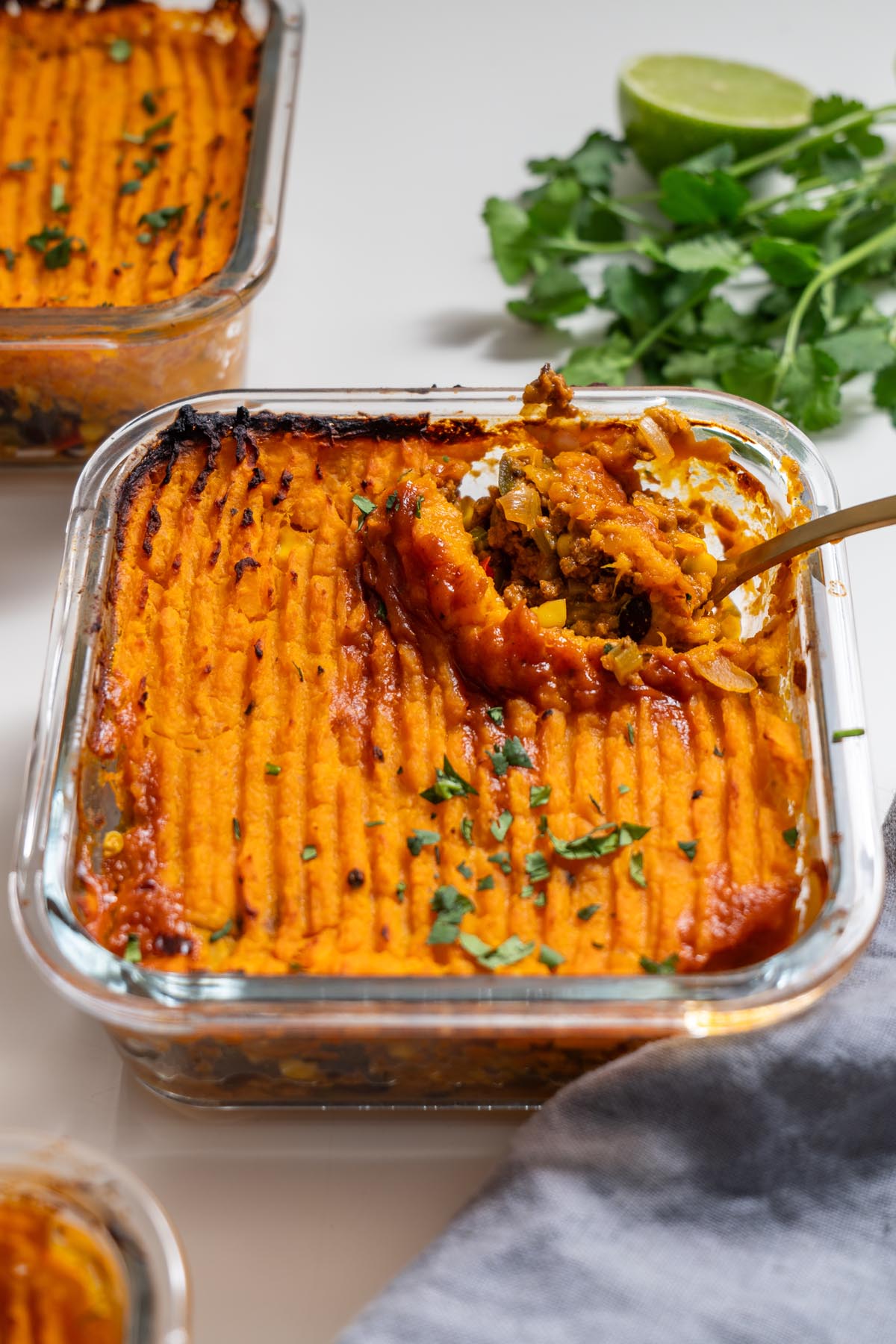 Baked Tex Mex Shepherd’s Pie with sweet potato mash topping in a glass dish with a spoon scooping out