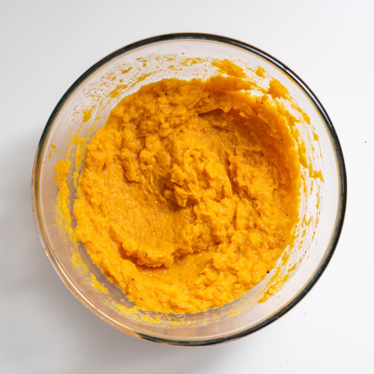Glass bowl of mashed sweet potato and butternut squash for Tex Mex Shepherd’s Pie on a white surface