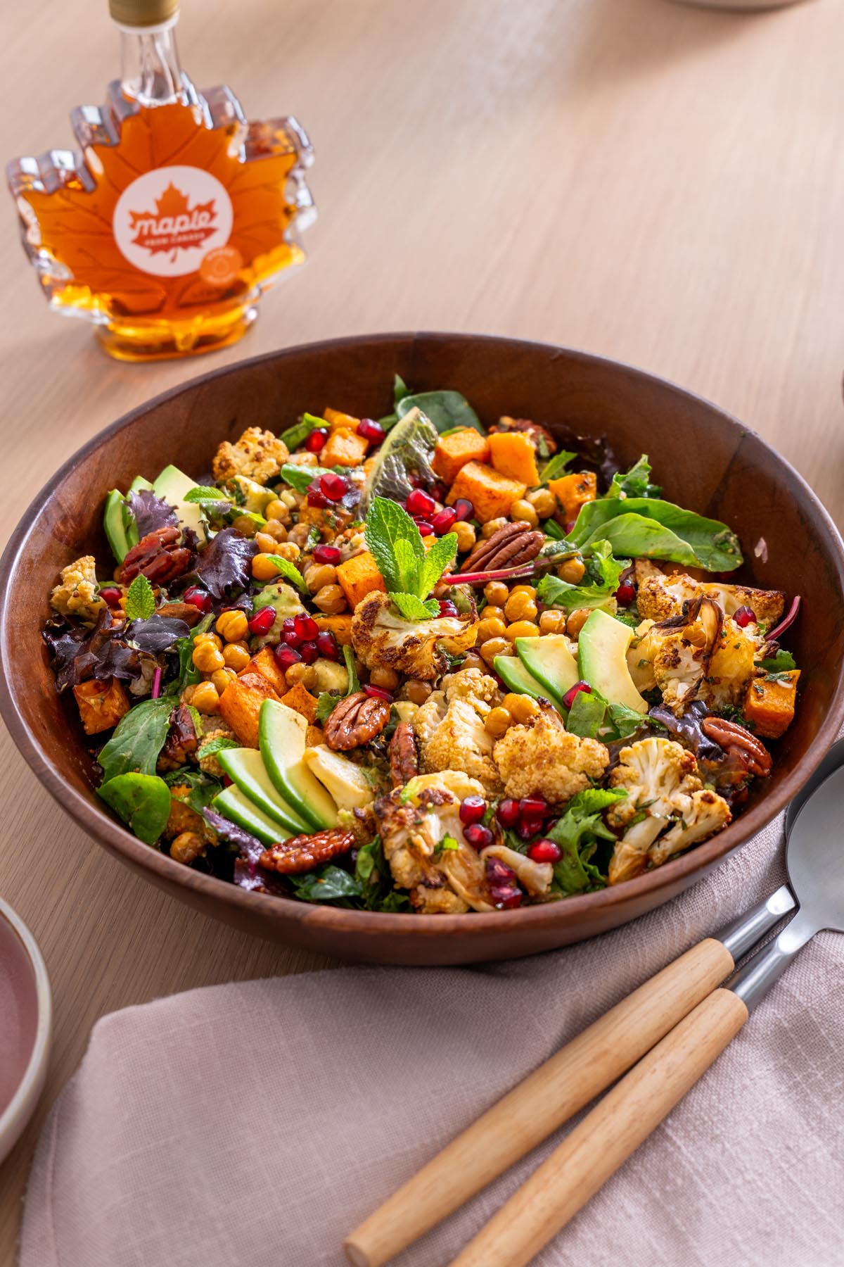 Món salad phong lễ hội được phục vụ trong bát gỗ với bí nướng, súp lơ, đậu xanh, quả bơ, hạt lựu và kẹo hồ đào trên bàn