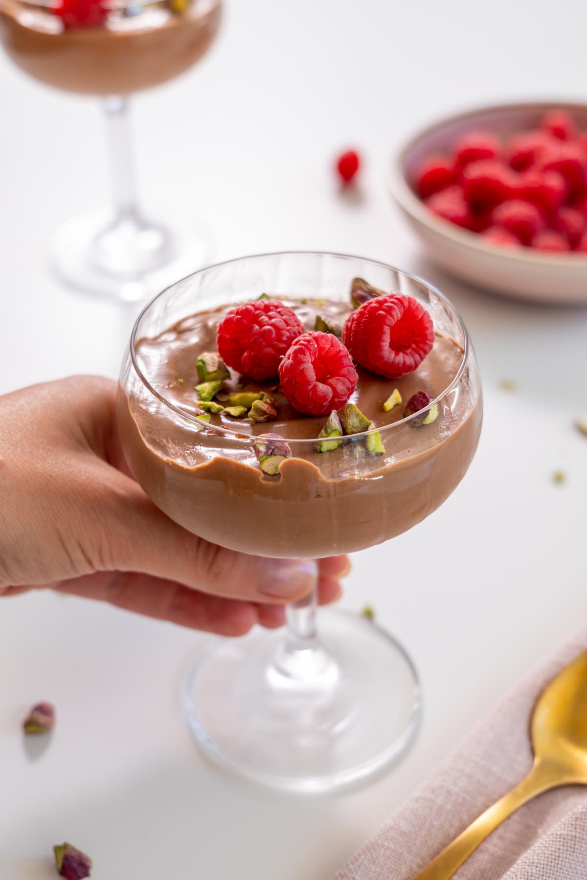 Sarah Cobacho holding a glass of chocolate mousse topped with raspberries and pistachios