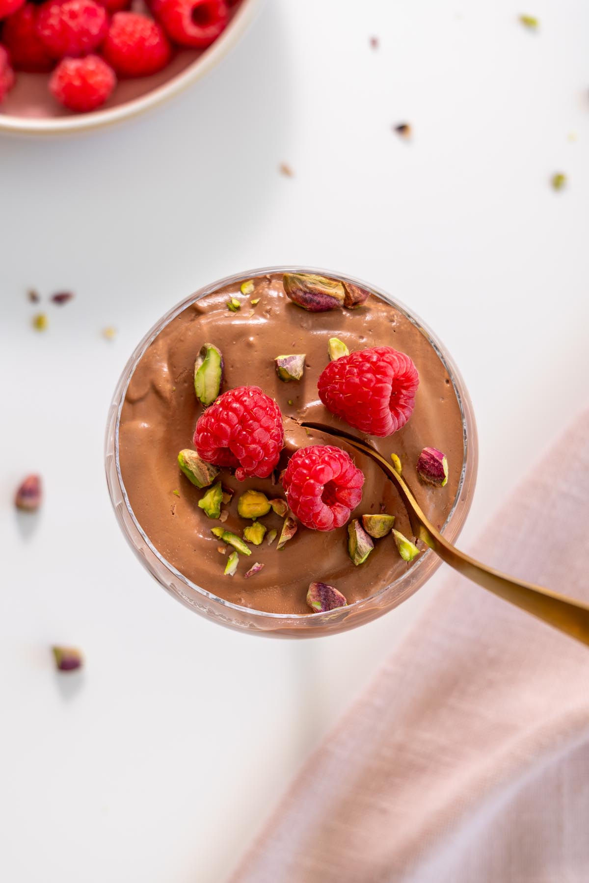 Top view of chocolate mousse topped with raspberries and pistachios
