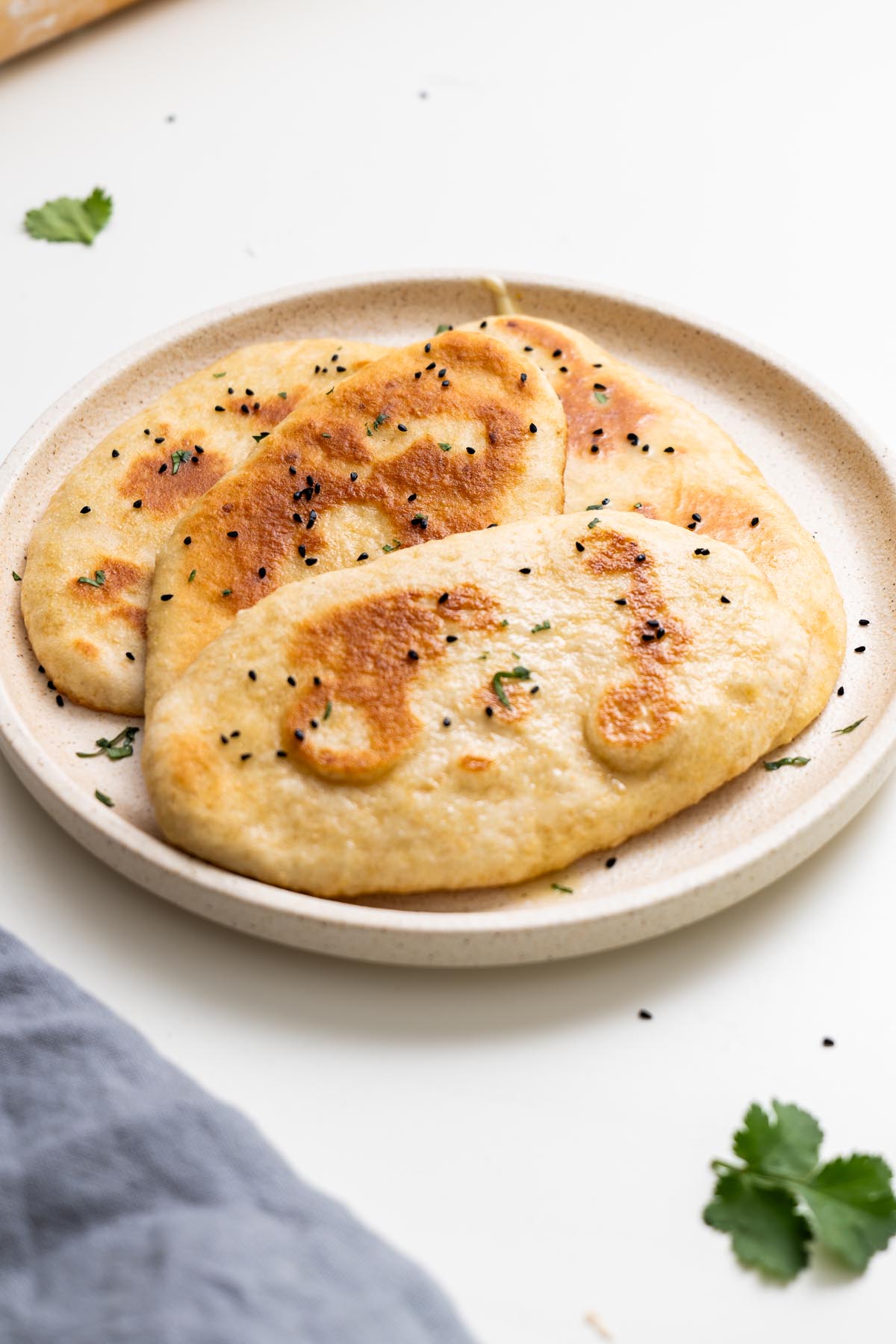 easy dairy-free naan breads on a plate with herbs and seeds