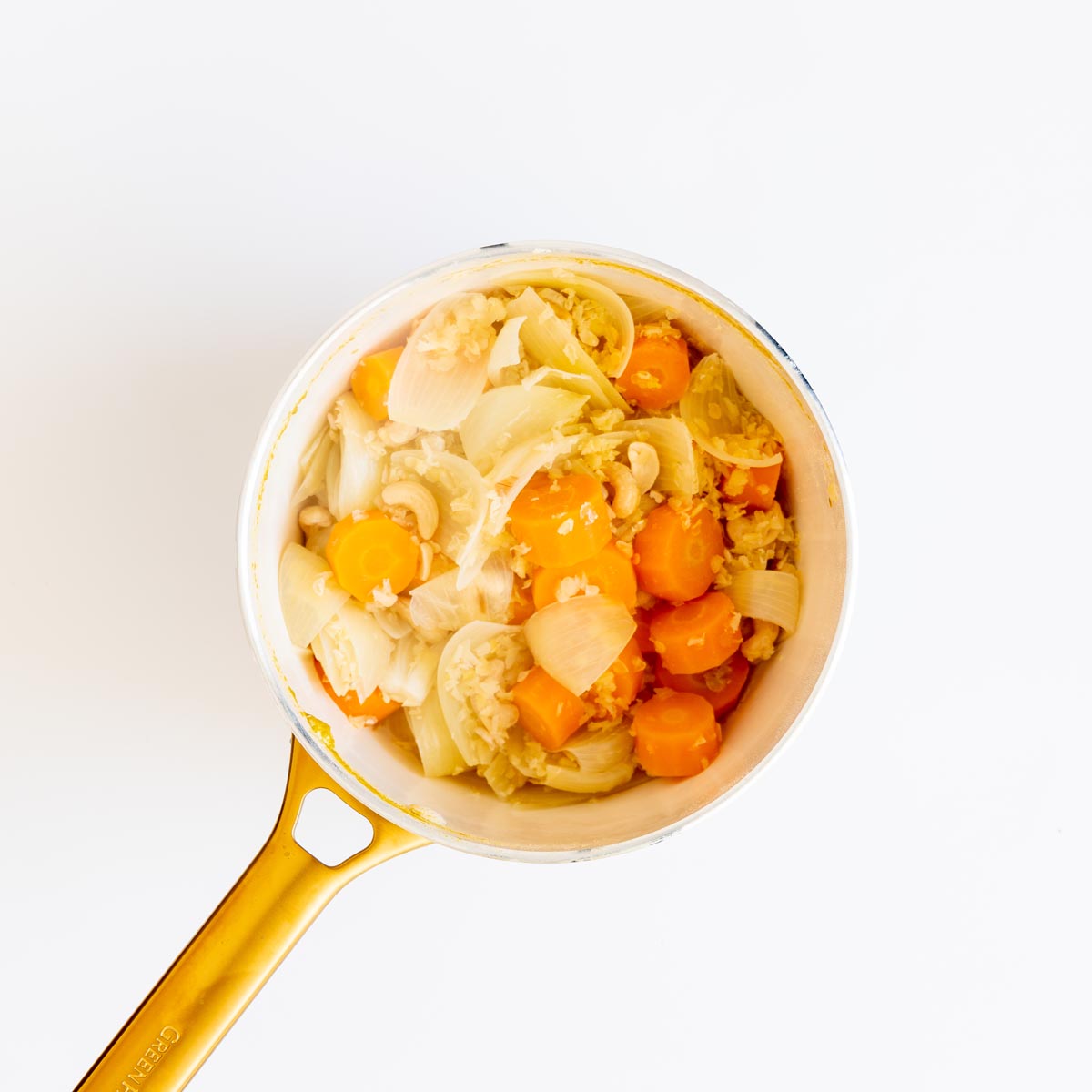 Cooked carrots, onions, cashews, and lentils in a pot before blending.