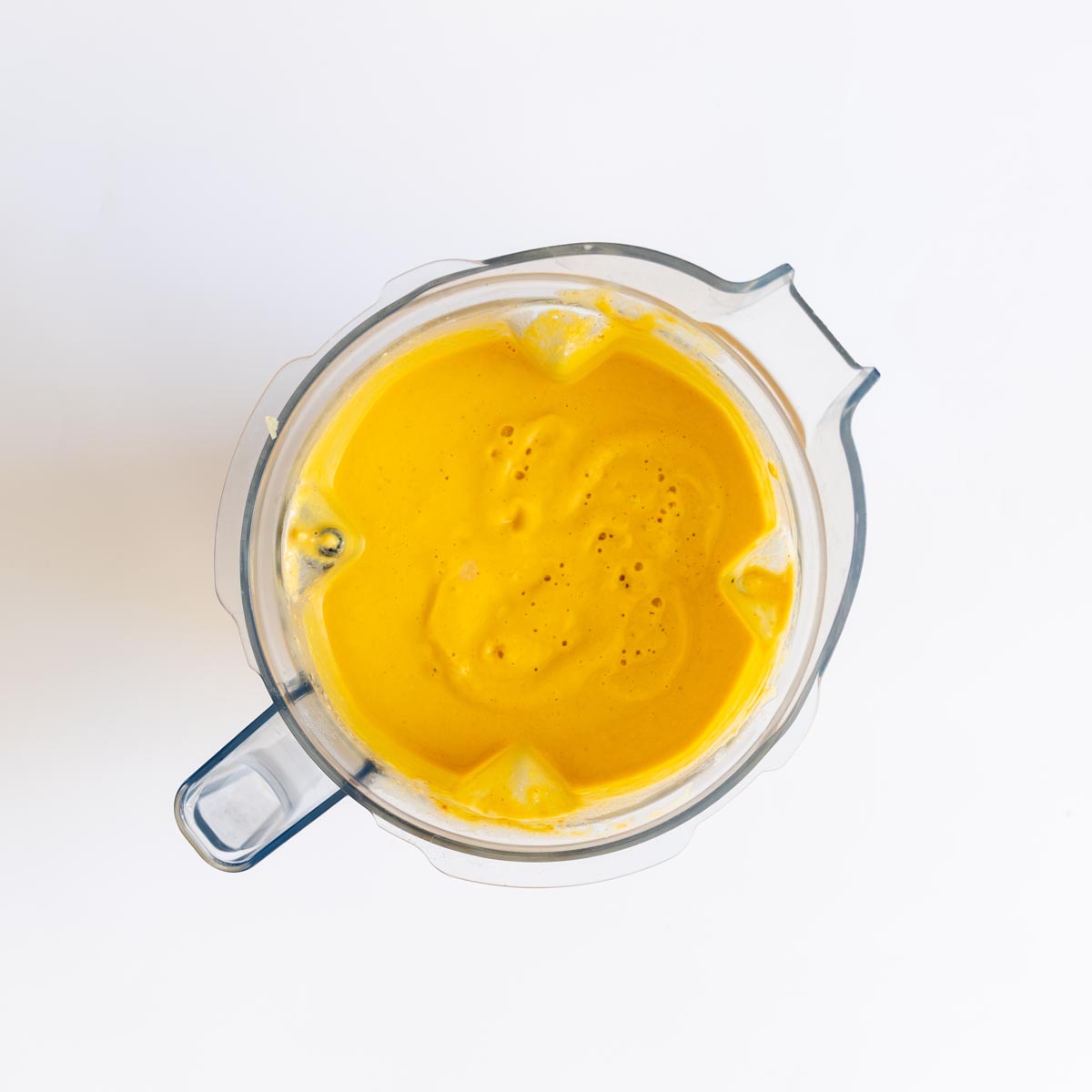 Bright orange blended lentil sauce inside a blender jug.