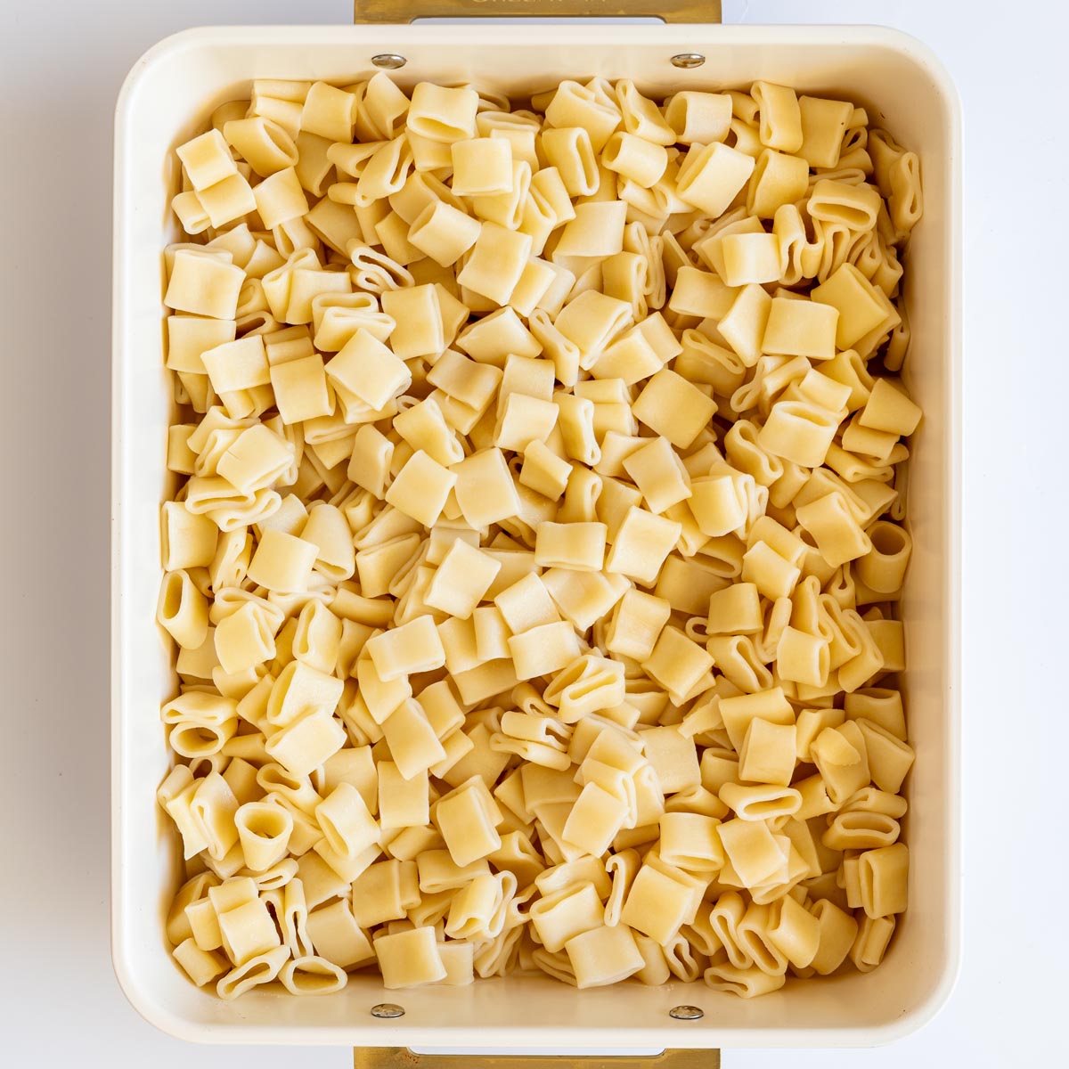 Cooked pasta spread evenly in a baking dish before assembling.