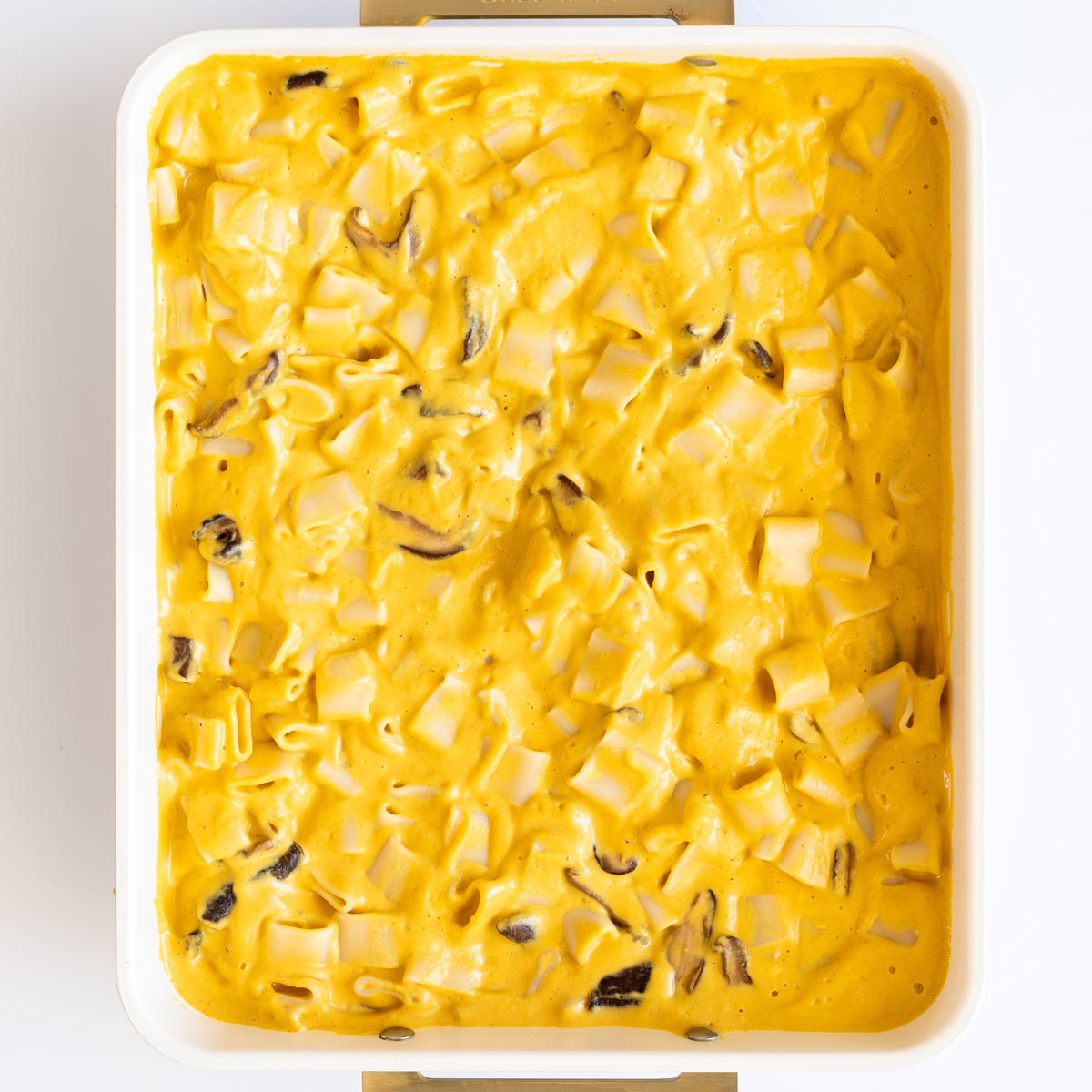 Baked vegan mac and cheese with sauce mixed through in a white baking dish