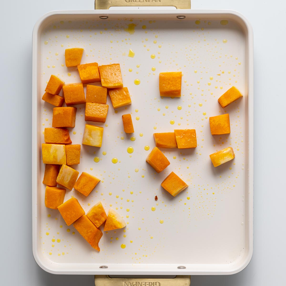 Pumpkin cubes spread across a baking tray with olive oil ready for roasting