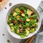 Holiday salad with greens, roasted vegetables, avocado, cranberries, pecans, and dill in a serving bowl
