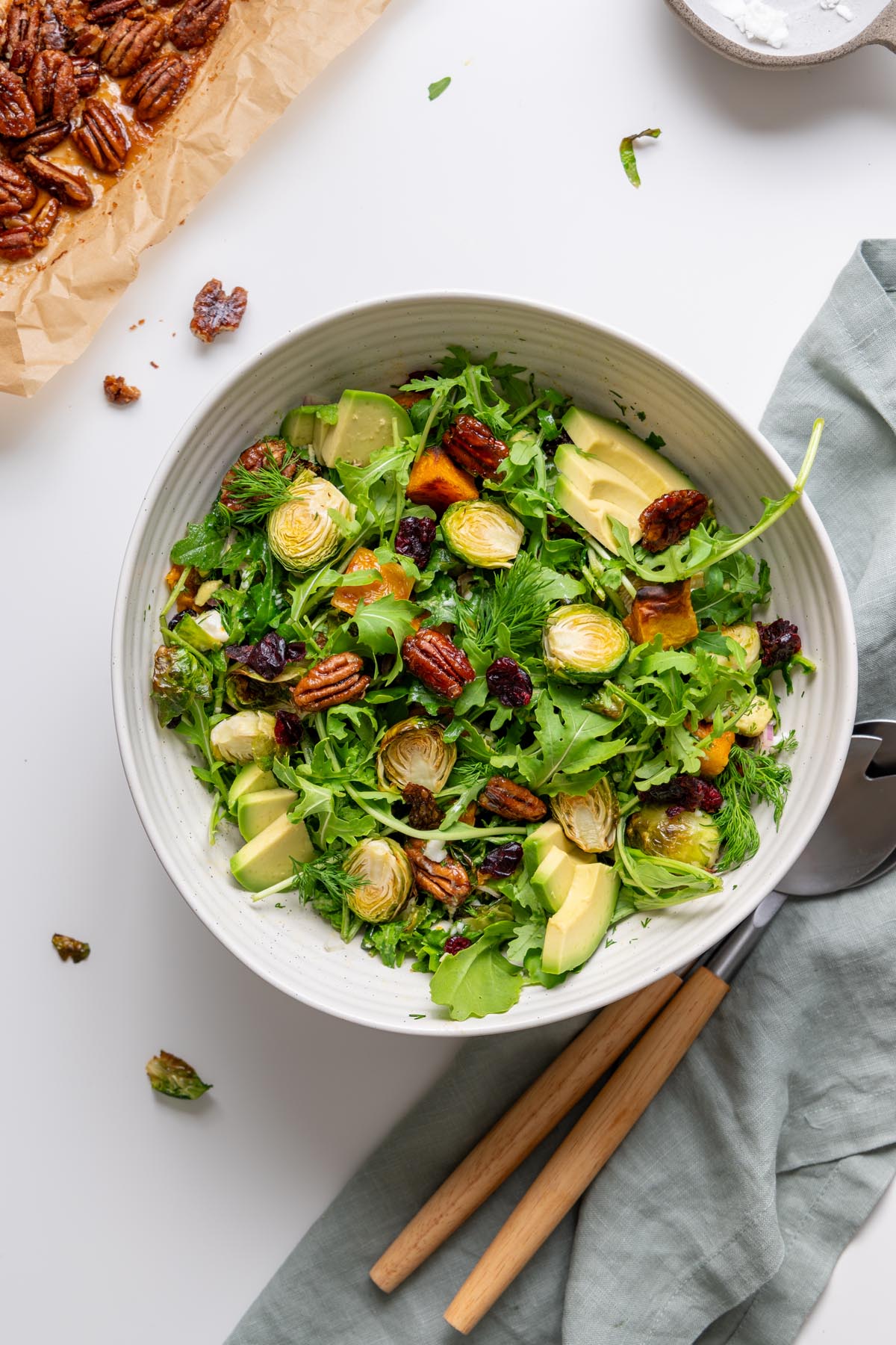 Holiday salad with greens, roasted vegetables, avocado, cranberries, pecans, and dill in a serving bowl