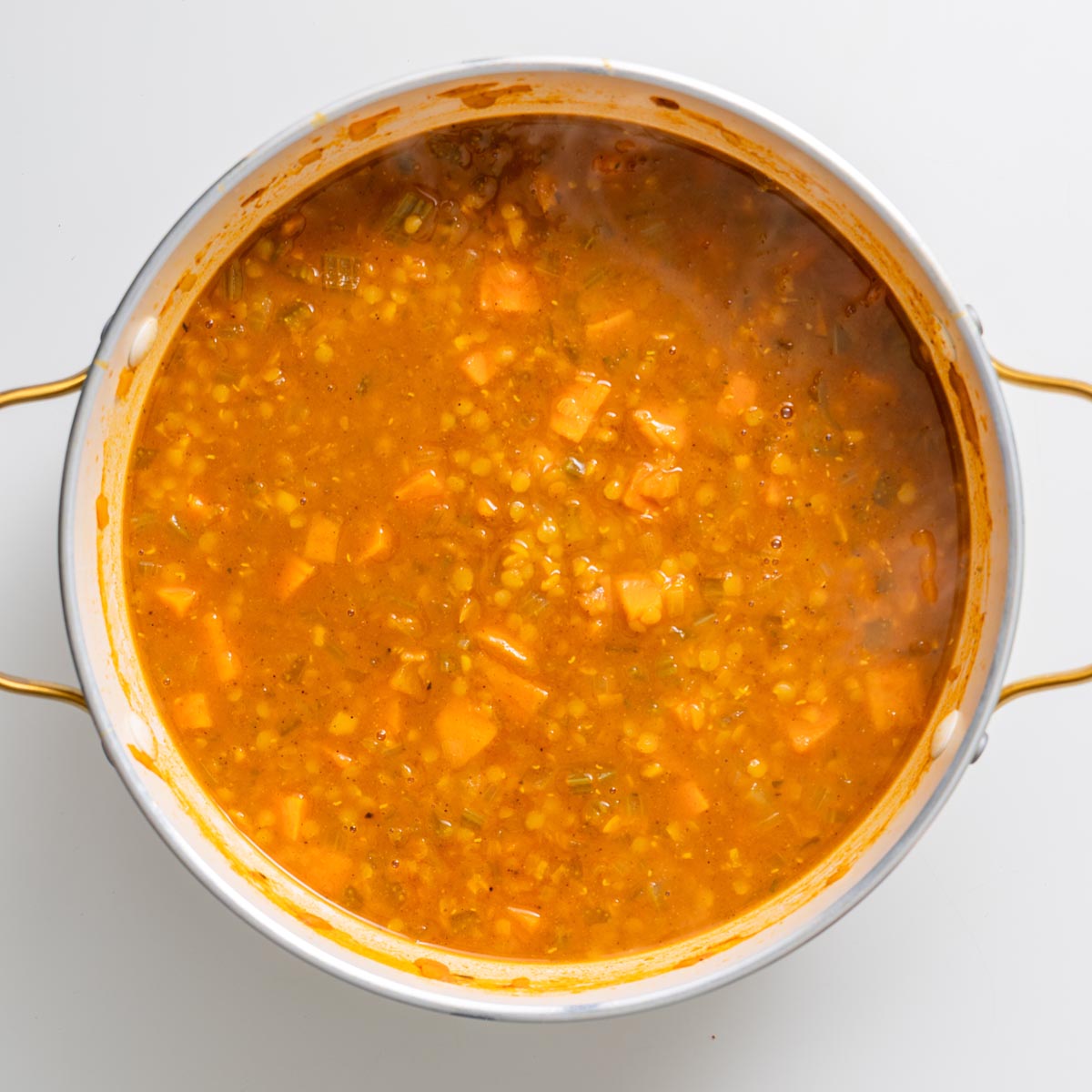 Large pot of simmering red lentil and sweet potato soup before adding greens.