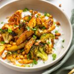 Close-up of roasted potatoes, broccoli, and chickpeas served on garlic yogurt sauce.