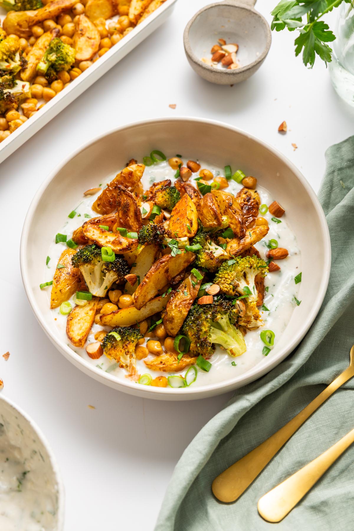 Top view of roasted potato bowl with broccoli and chickpeas over creamy garlic yogurt.