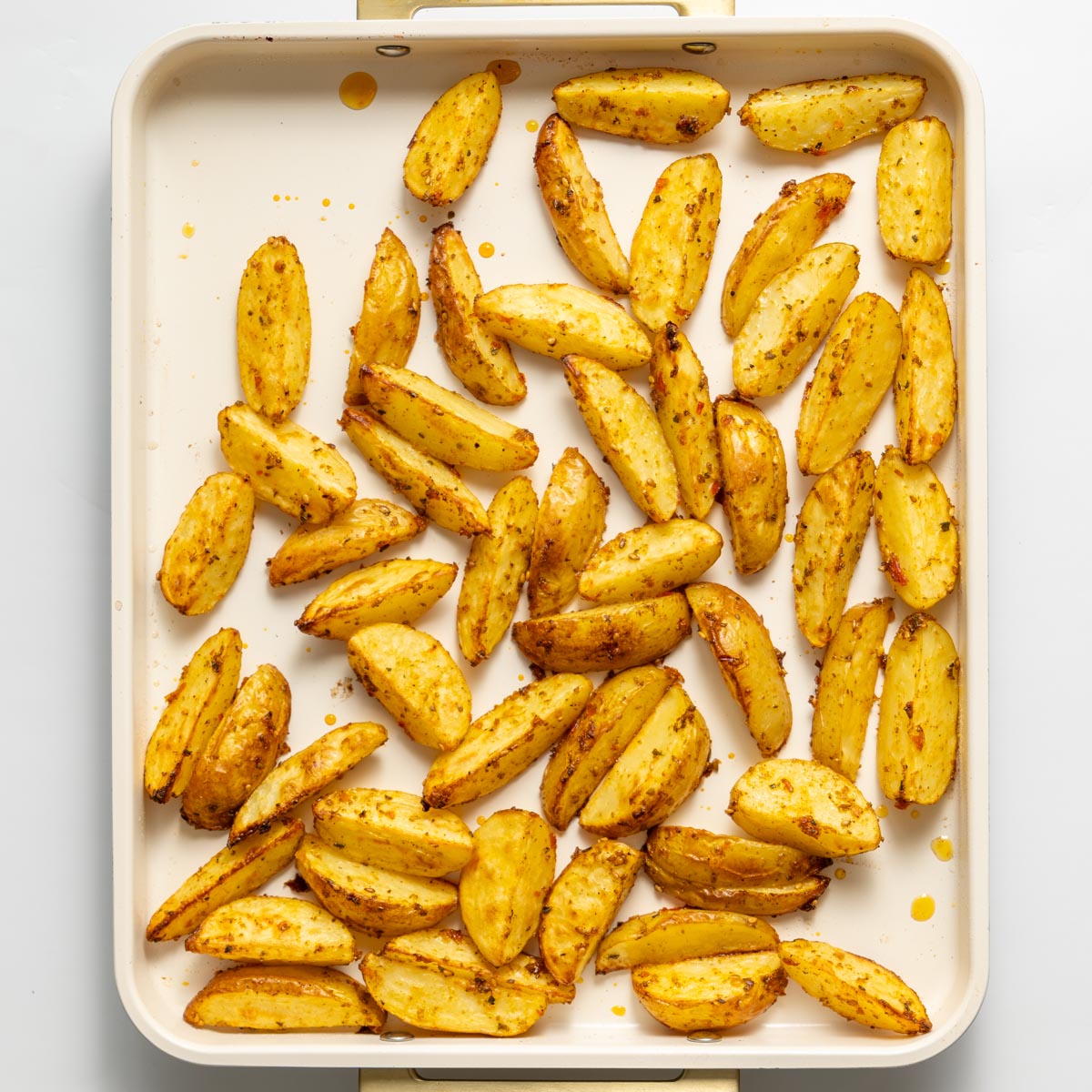 Roasted seasoned potato wedges on a baking tray