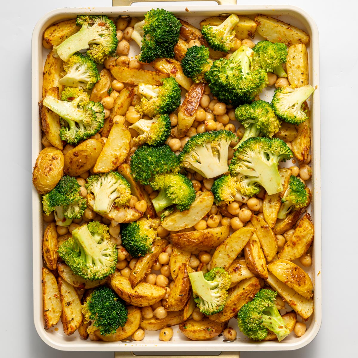 Roasted potatoes, broccoli, and chickpeas on a baking tray after roasting.