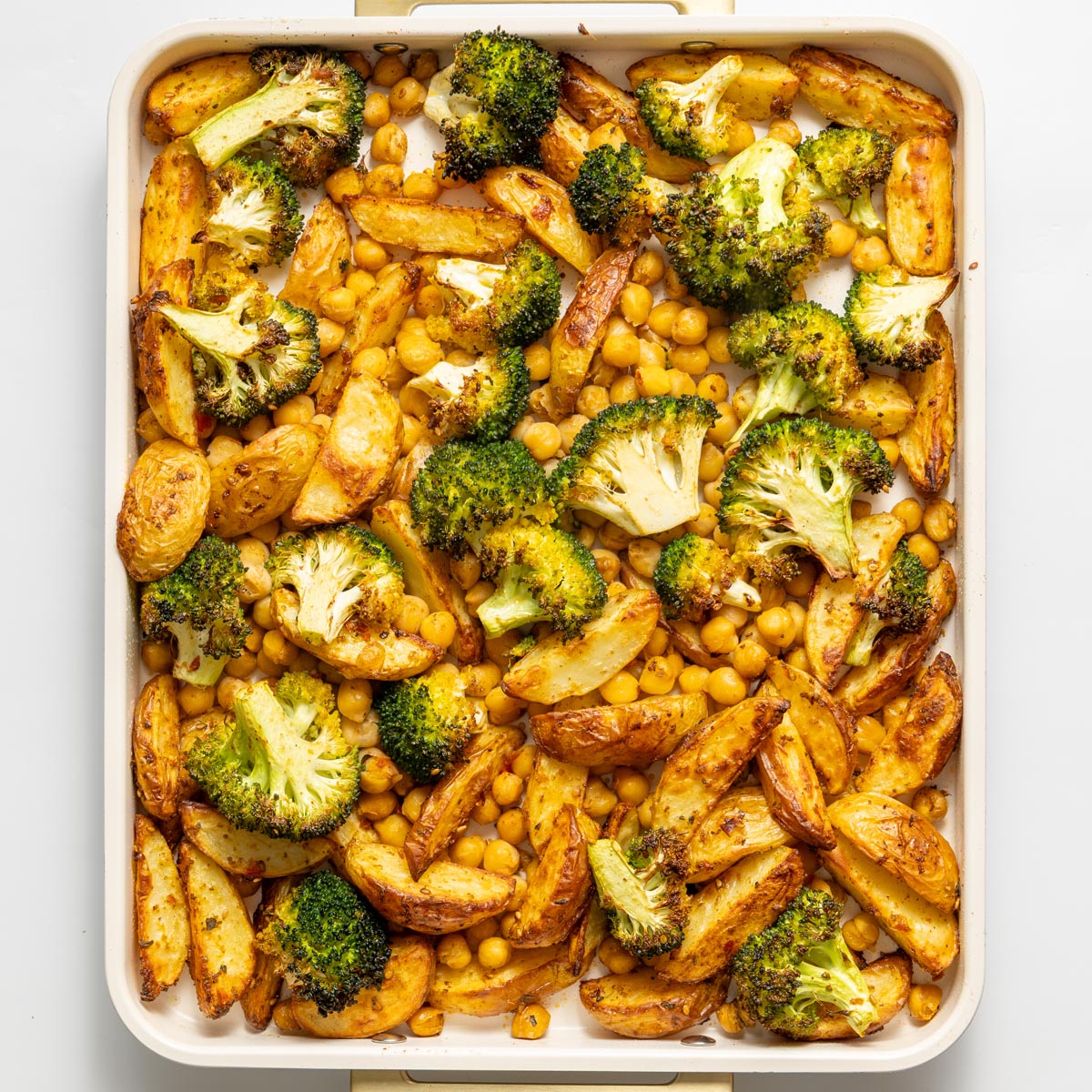 Crispy roasted potatoes, broccoli, and chickpeas on a baking tray fresh from the oven.