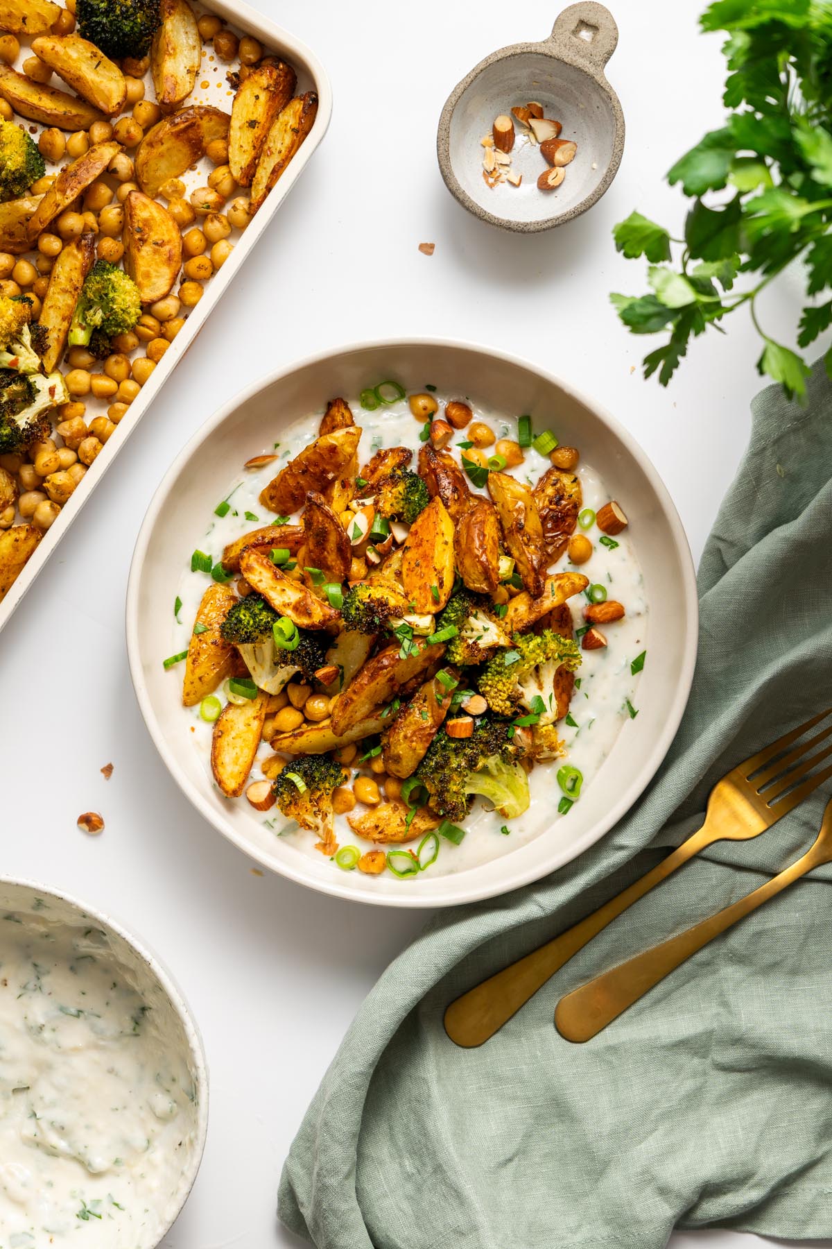 Roasted potato bowl with chickpeas, broccoli, and almonds served over garlic yogurt sauce.