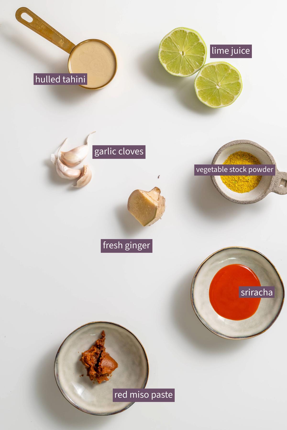 Labeled ingredients for miso tahini sauce on a white surface.