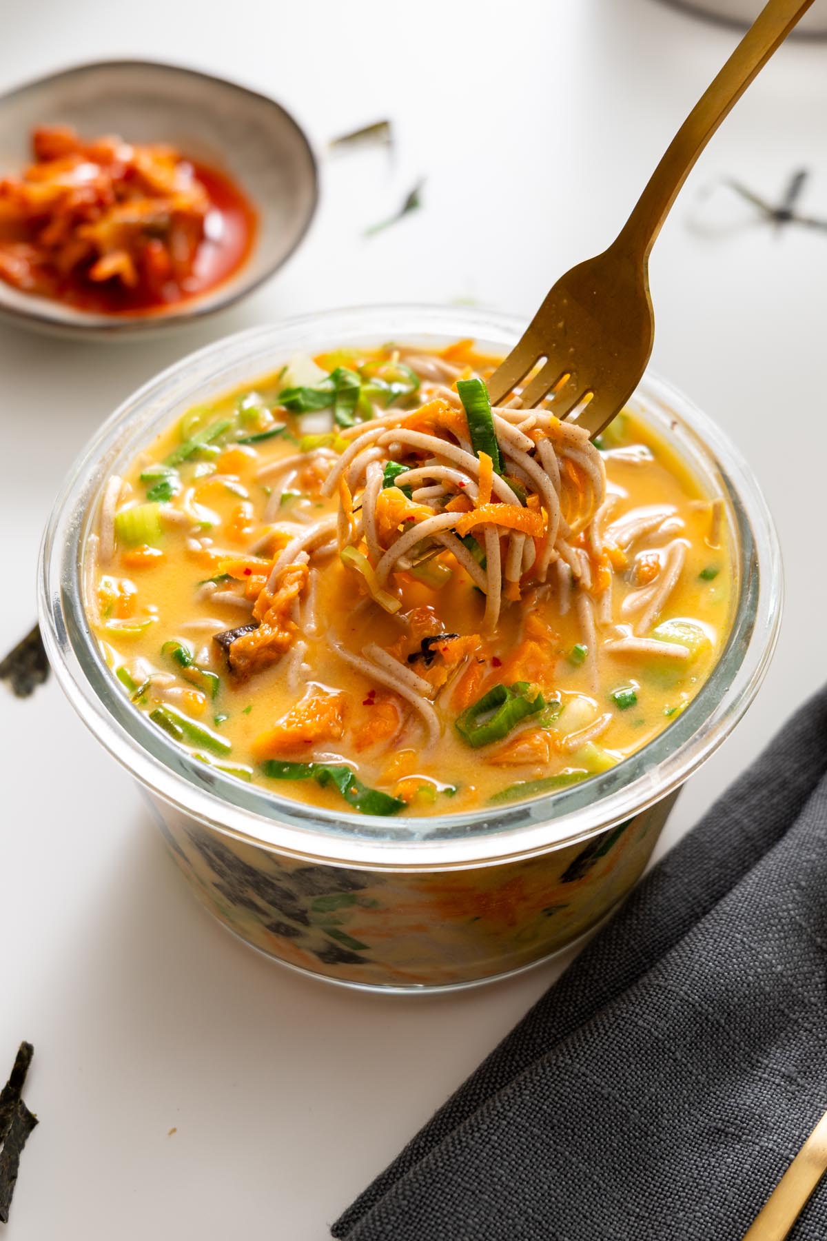 Fork twirling soba noodles from miso noodle soup meal prep container.