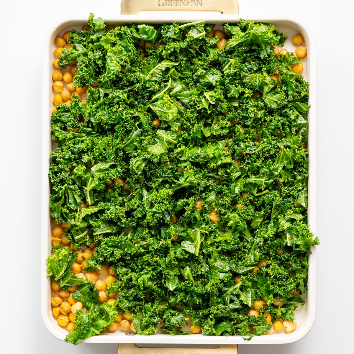 Fresh kale and chickpeas on a baking tray ready to be roasted as toppings for roasted cauliflower and red bell pepper soup.