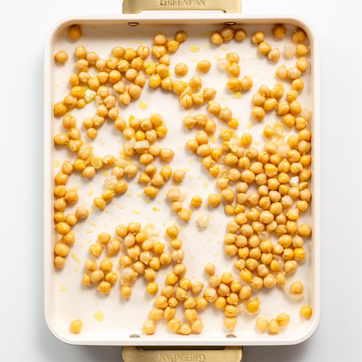Chickpeas spread on a baking tray with olive oil, ready to be roasted for soup toppings.