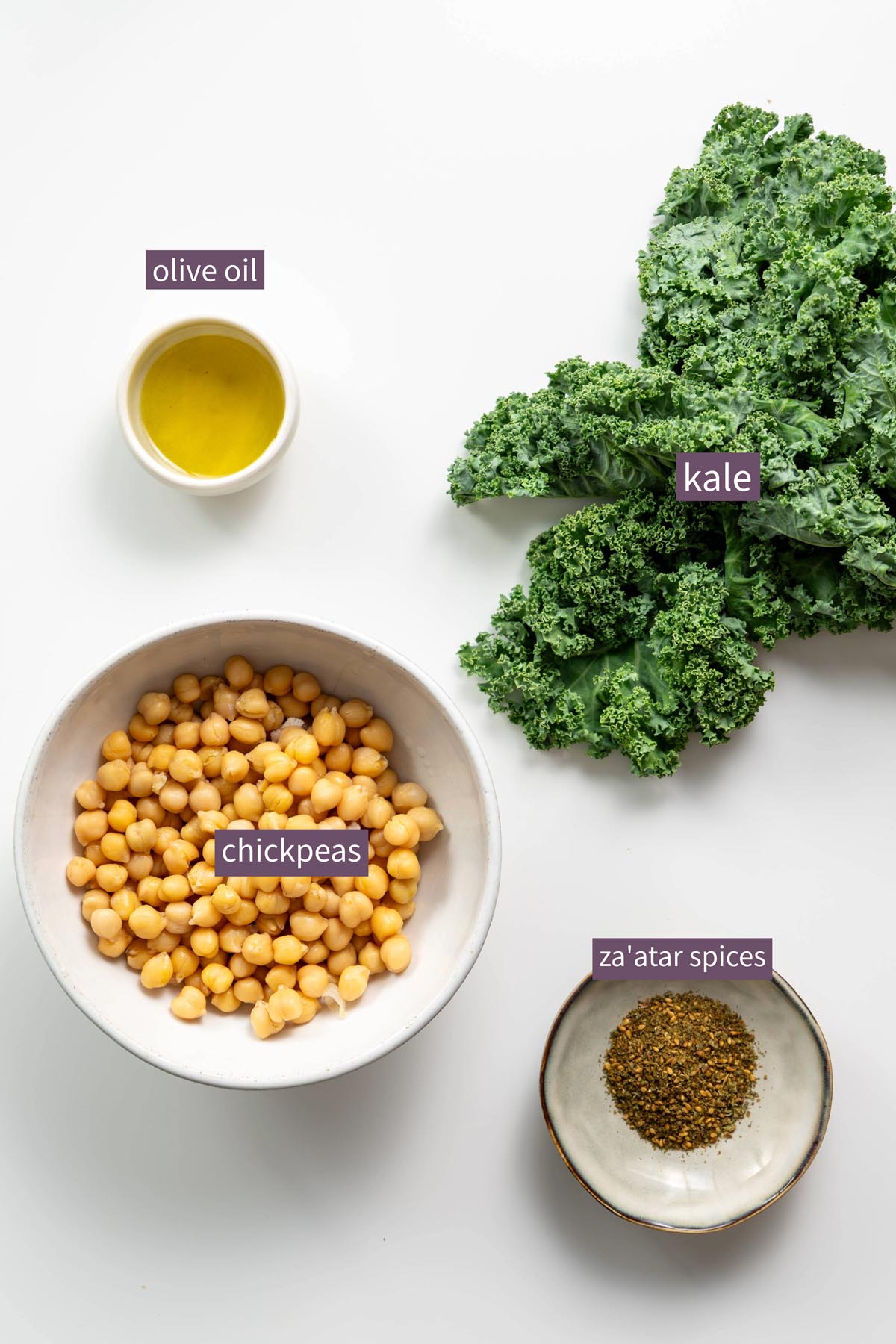 Topping ingredients for roasted cauliflower and red bell pepper soup, including fresh kale, chickpeas, olive oil, and za'atar spices.