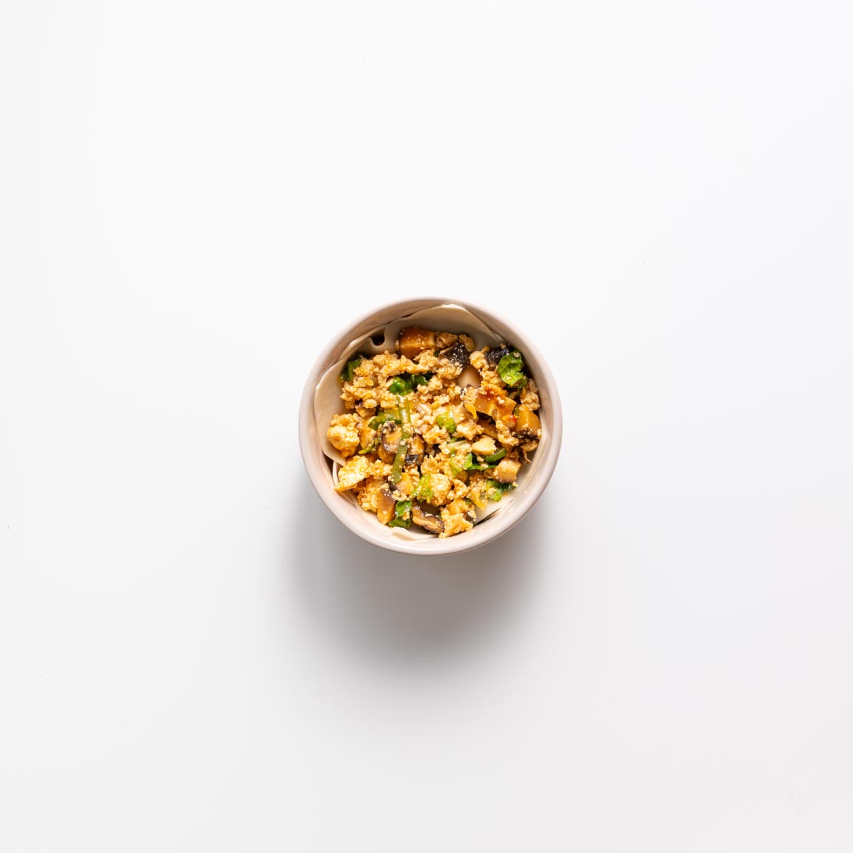 Layering wonton wrapper and filling in a small pink bowl for dumpling soup lasagna