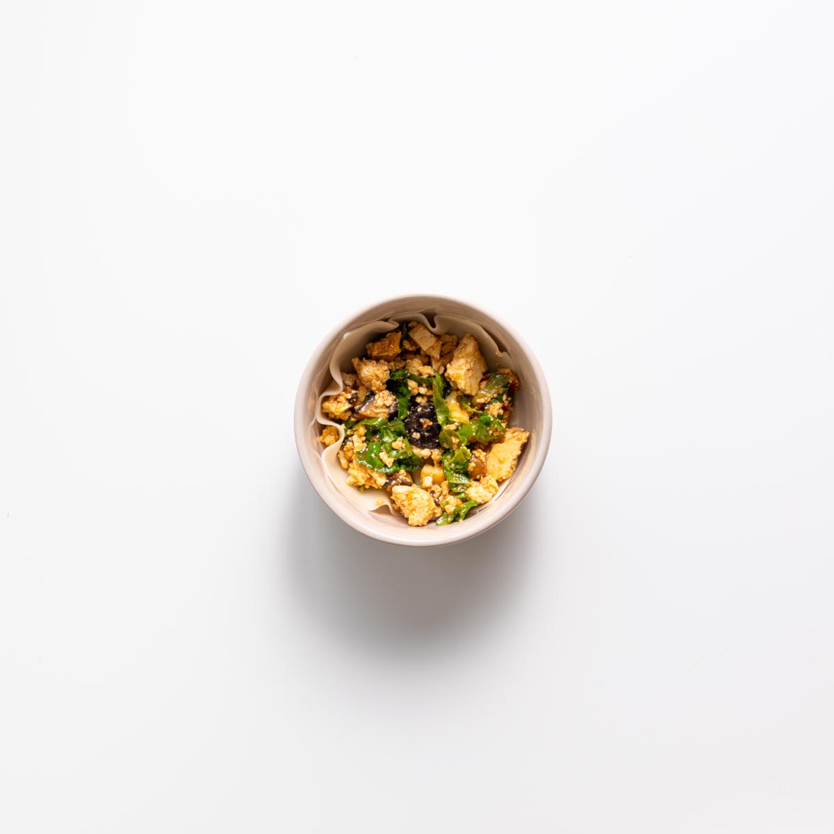 Layering wonton wrapper and filling in a small pink bowl for dumpling soup lasagna