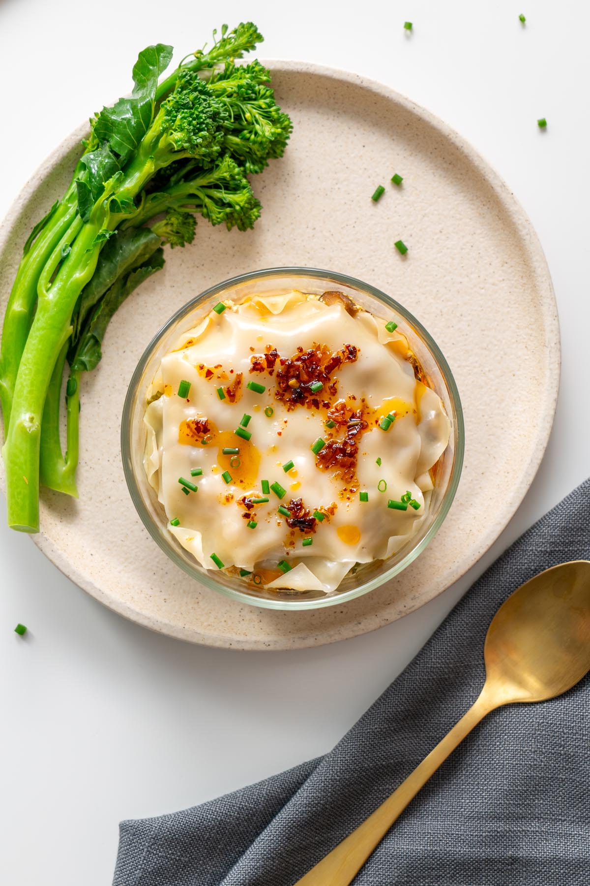 Steamed soup dumpling lasagna in a glass bowl with broccolini on the side.