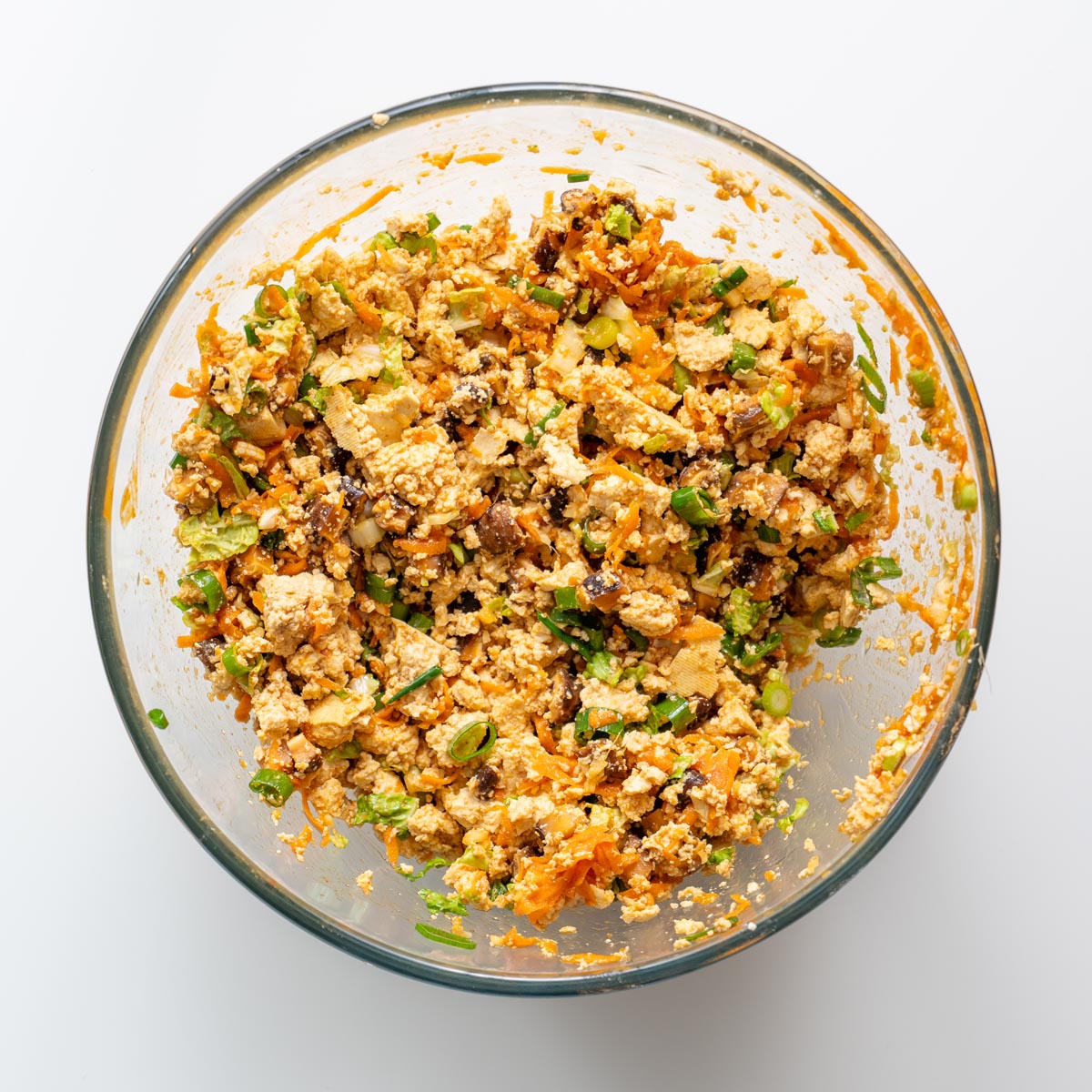 Overhead view of mixed tofu and vegetable filling for soup dumpling lasagna in a glass bowl.