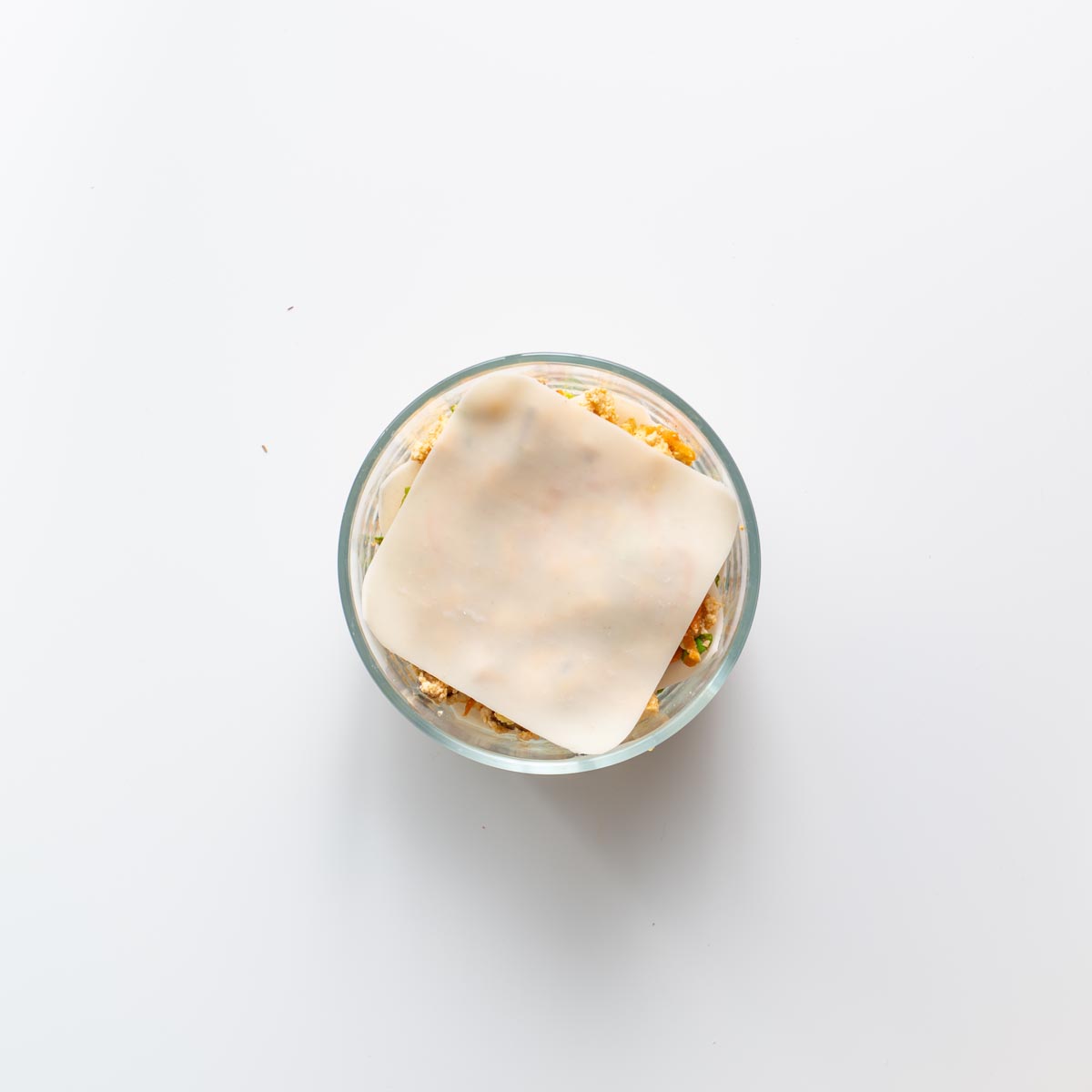 Step by step view of layering soup dumpling lasagna in a glass bowl.