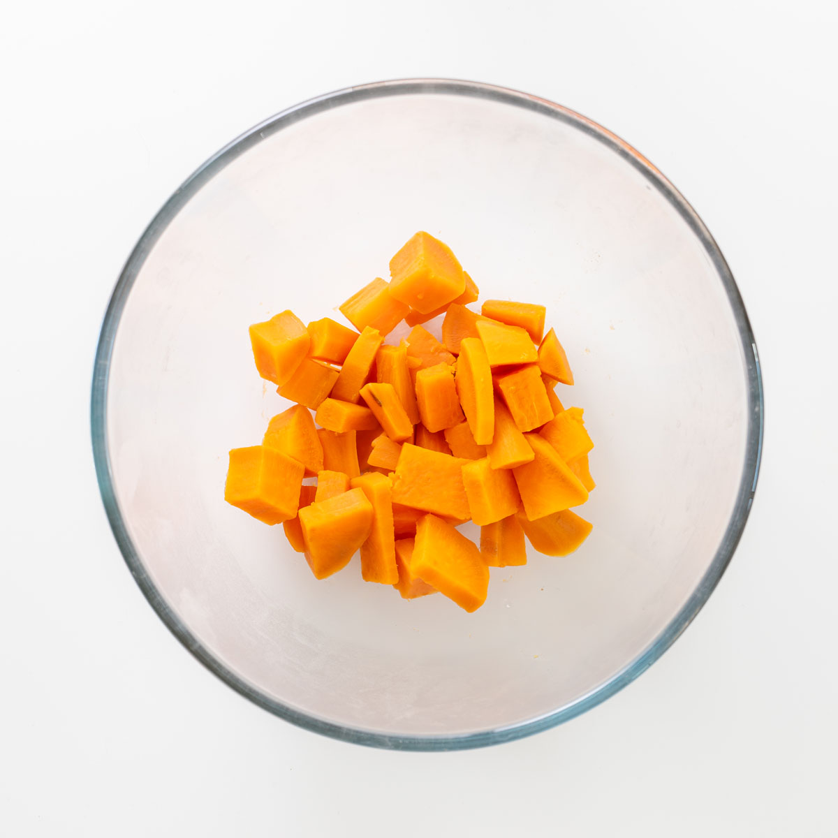 Peeled and chopped sweet potato cubes in a glass bowl.