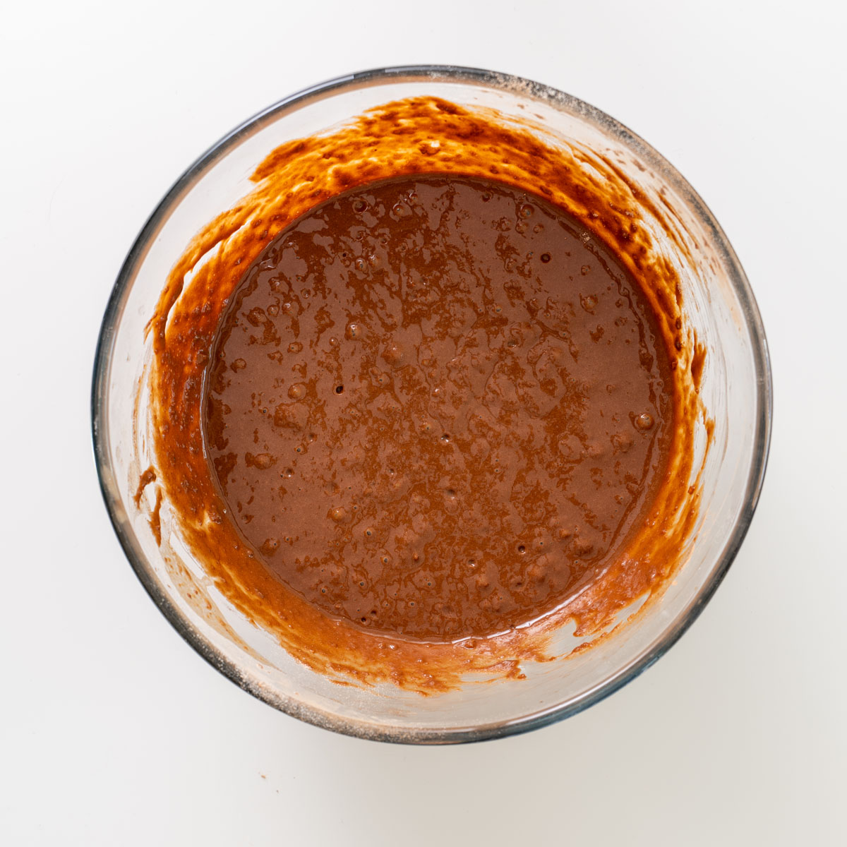 Smooth chocolate brownie batter in a glass mixing bowl.