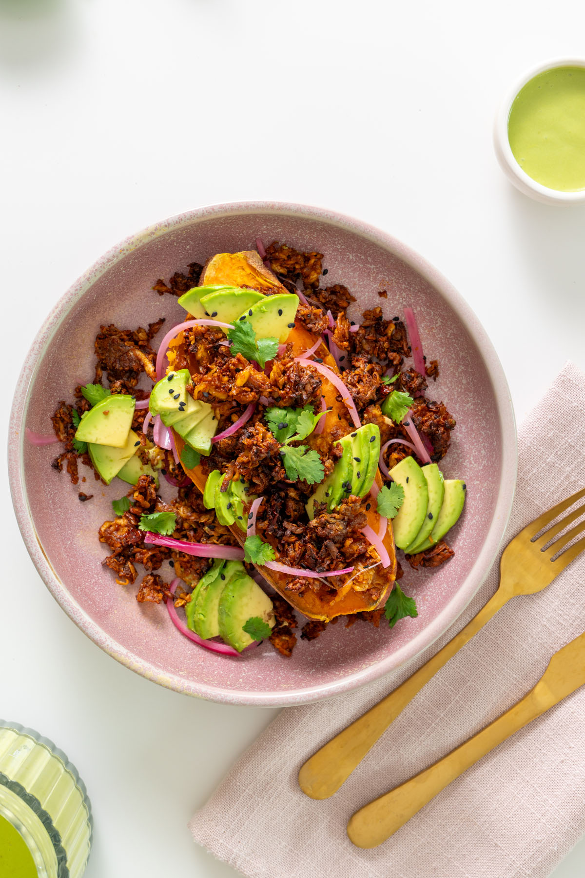 High-protein chipotle sweet potato bowl served in a pink bowl with crispy chipotle tofu, avocado, pickled onions, and cilantro.