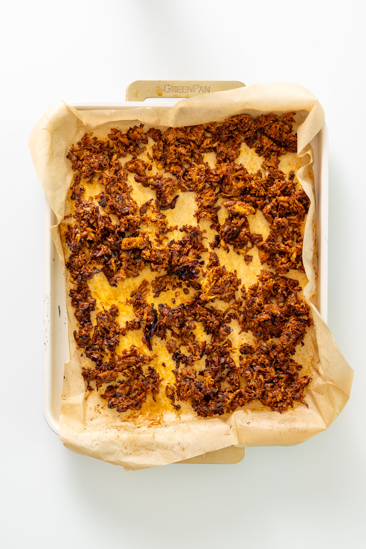 Baked crispy chipotle tofu crumbles spread on a parchment-lined baking tray after roasting.