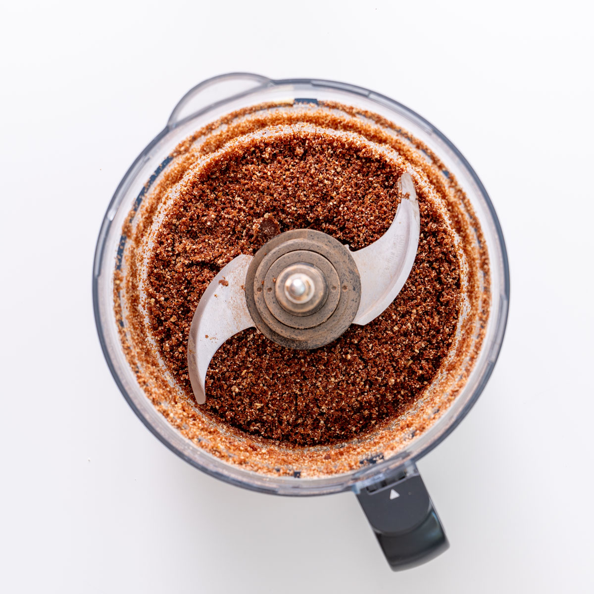 Hazelnut date cacao crust mixture in a food processor bowl before pressing into the tart pan.