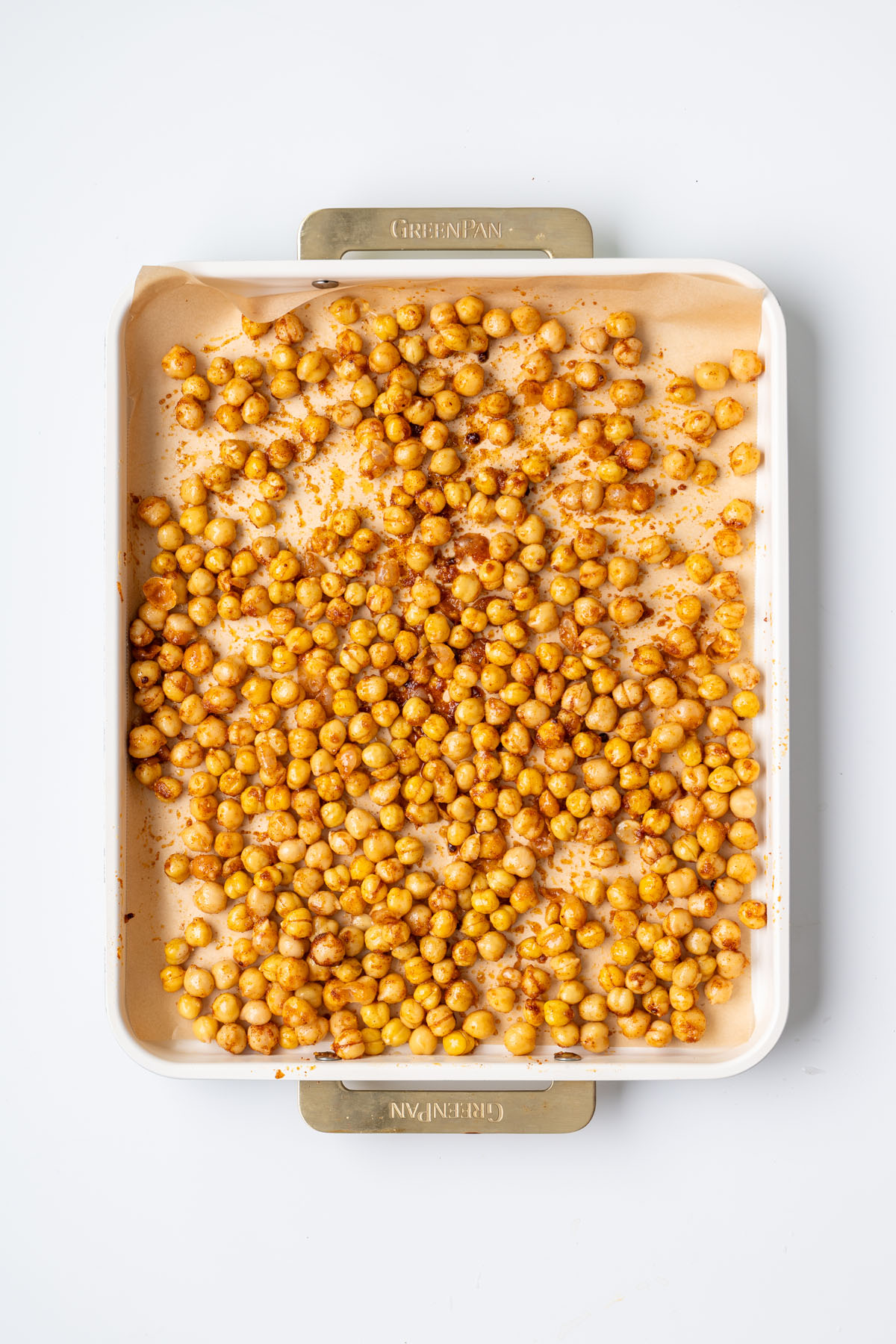 Seasoned chickpeas with smoked paprika and spices on a parchment-lined baking tray before roasting