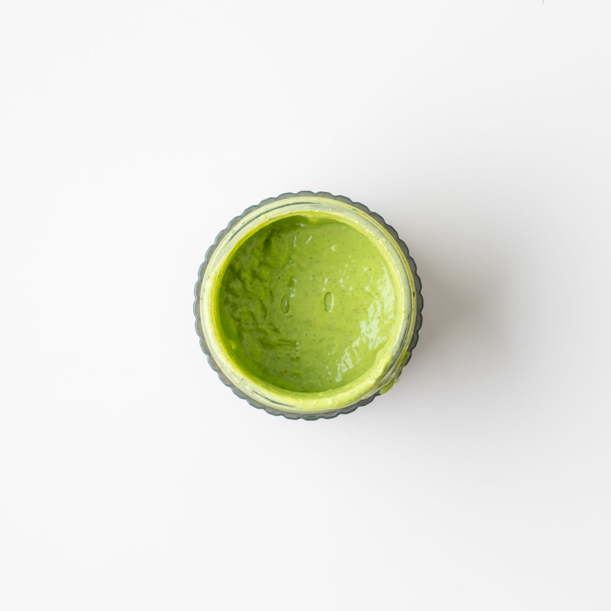 Creamy avocado ranch dressing in a glass jar viewed from above on a white surface