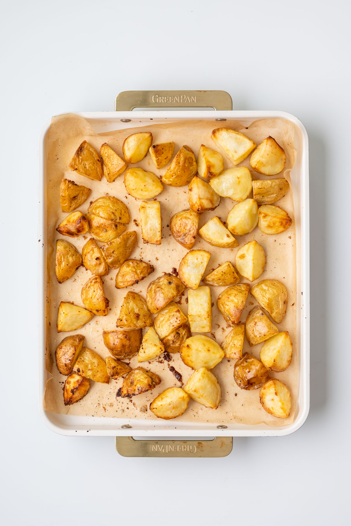 Golden roasted potatoes on a parchment-lined baking tray