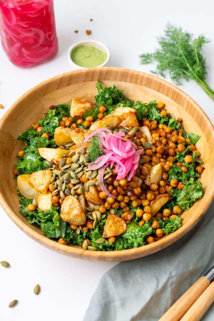 Roasted potato and avocado ranch salad in a wooden bowl with crispy chickpeas, kale, pumpkin seeds, and pickled red onion, styled with avocado ranch dressing and fresh dill